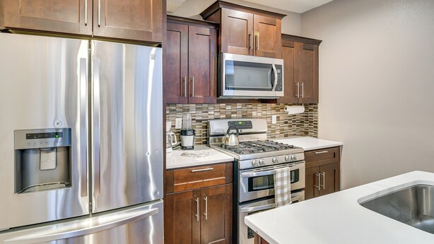 A kitchen with stainless steel appliances, wooden cabinets, a microwave, a stove, and a sink. - 4 Mi to Easter Lake Park! Inviting Rental w/ Patio (Des Moines)
