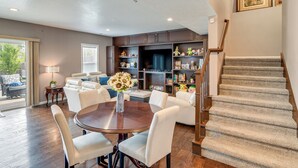 A living room with a round table, white chairs, a sofa, a staircase, and a bookshelf with various items. - 4 Mi to Easter Lake Park! Inviting Rental w/ Patio (Des Moines)