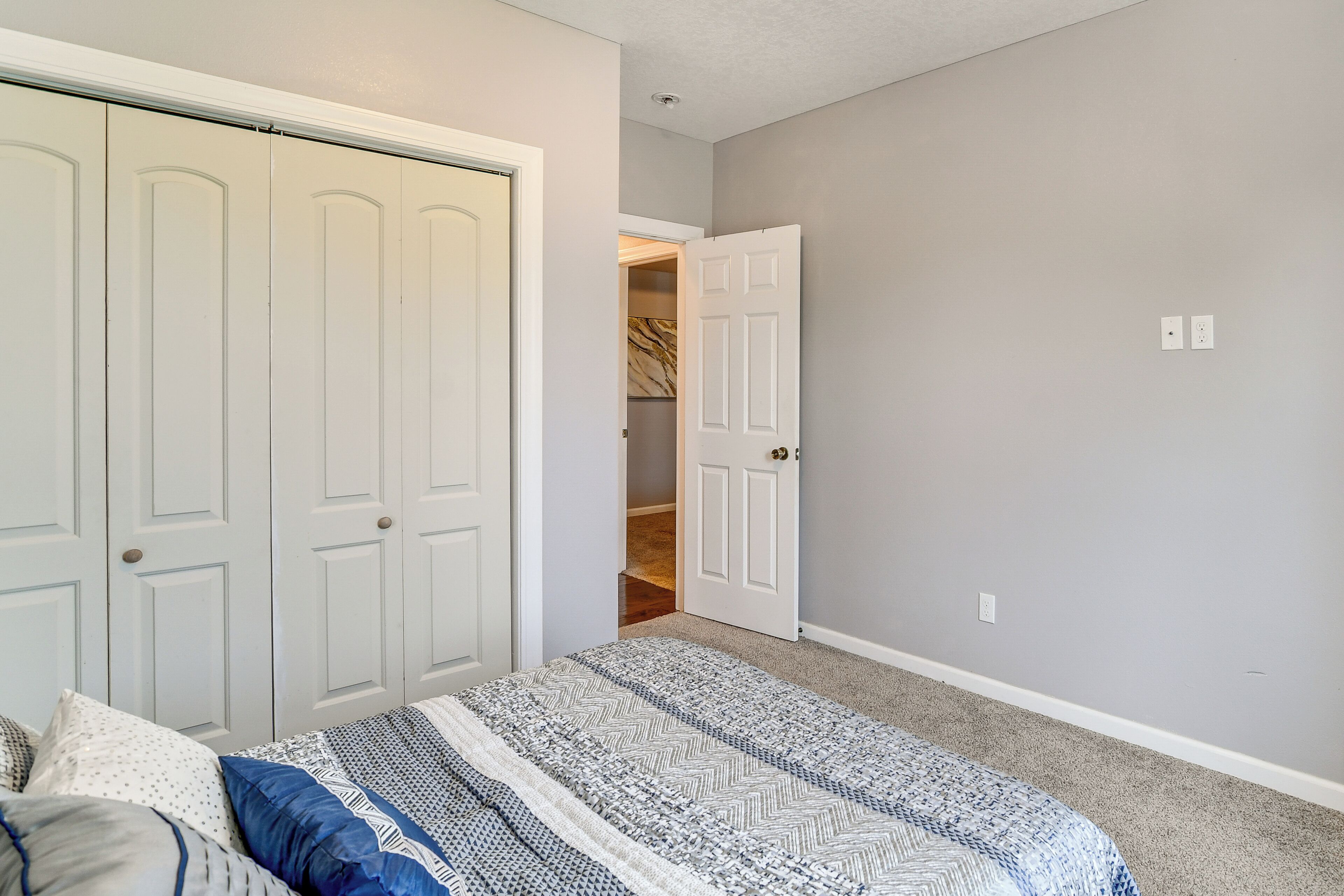A bedroom with a bed, a closet, and a door leading to a hallway.
