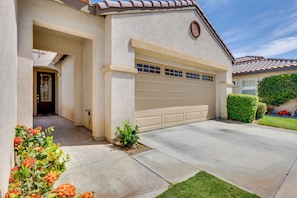 A residential house with a garage, a front door, and a small garden with flowers. - Pool Access + Mtn Views! Extended Escape in Indio (Indio)