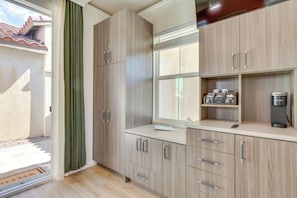 A kitchen with wooden cabinets, a window, and a coffee maker. - Pool Access + Mtn Views! Extended Escape in Indio (Indio)