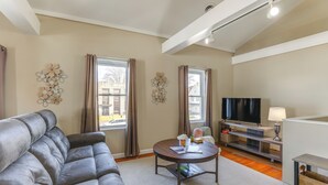 Ein Wohnzimmer mit grauem Sofa, einem runden Couchtisch, einem Fernseher und einer Lampe.