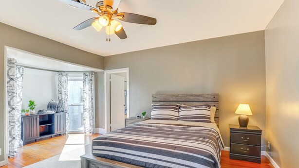 Ein Schlafzimmer mit Bett, Nachttisch, Deckenventilator und Blick auf einen Balkon.