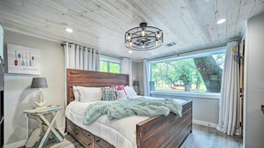 A bedroom with a wooden bed, a nightstand, a lamp, and a window with curtains. - Blanco Riverfront Estate w/ 2 Homes: 4-Acre Oasis (Blanco)