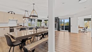Une cuisine moderne dotée d’un grand îlot central, de luminaires suspendus et offrant une vue sur l’extérieur.
