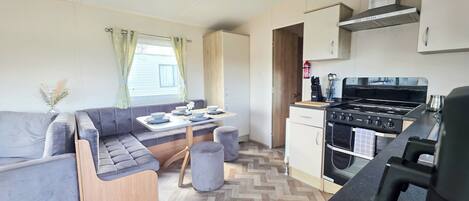 A compact kitchen with a stove, oven, and a dining area with a bench and table.