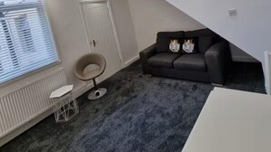 Ein modernes Wohnzimmer mit einer schwarzen Ledersofa, einem runden Sessel und einer außergewöhnlichen Deckenleuchte.