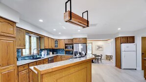 A modern kitchen with wooden cabinets, a granite countertop, and a built-in island. - Large Poconos Group Retreat with Hot Tub and Game Room (Albrightsville)