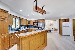 A modern kitchen with wooden cabinets, a granite countertop, and a built-in island. - Large Poconos Group Retreat with Hot Tub and Game Room (Albrightsville)