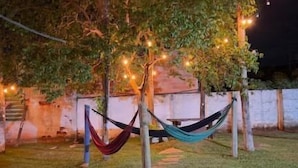 A hammock between trees in a grassy area with string lights. - Chalés Bela Vista (Pirenopolis)