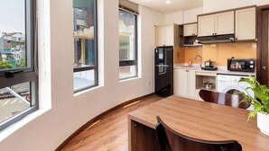 A modern kitchen with a built-in refrigerator, microwave, and sink. There is a dining table with chairs and a potted plant. - Luxury 1-bedroom Apt, Elevator; Kitchen; Washing&Dryer; 800m to TSN Airport (Thành phố Hồ Chí Minh)