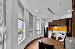 Eine moderne Küche mit Einbauofen, Waschmaschine und Essbereich mit Holztisch und Stühlen.