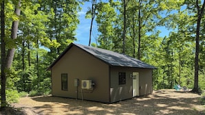 Une petite cabane avec un toit en métal, une porte et un appareil de climatisation fixé sur le côté.