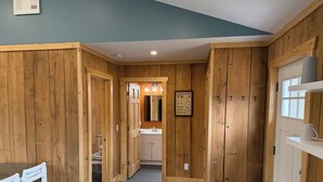 Un intérieur en bois comprenant un coin repas, une cuisine et une salle de bain.