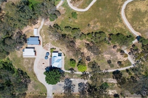 An aerial view of a property with a central building, multiple smaller structures, and surrounding greenery.