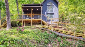A cabin with a wooden deck, a staircase, and a large window. - Pine and Peak – Hot Tub, Fire Pit, Dog Friendly (Gatlinburg)