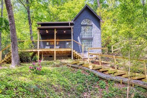 A cabin with a wooden deck, a staircase, and a large window. - Pine and Peak – Hot Tub, Fire Pit, Dog Friendly (Gatlinburg)