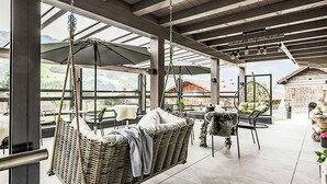 A spacious outdoor area with a hanging chair, a table, and chairs. - 2A Morgensonne/mit Weitblick by Interhome (Bad Hofgastein)