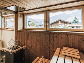 Ein Holzinnenraum mit Blick aus dem Fenster auf eine Berglandschaft, einem Wäscheständer und einer hölzernen Bank.