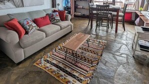 A living room with a sofa, coffee table, patterned rug, and a painting on the wall. - Troll Hill Nordic Nature Retreat (Municipality Of Chatham-Kent)