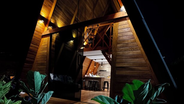 A wooden A-frame structure with a dining area and kitchen visible inside. - Hidden Luxury Cabin in Nature Jacuzzi, Fire Pit & Private Escape (Gobierno Regional de Lima)