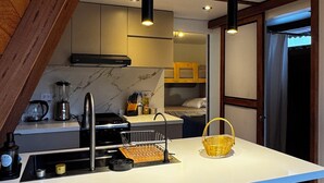 A compact kitchen with a central island, bar stools, and a hanging light fixture. - Hidden Luxury Cabin in Nature Jacuzzi, Fire Pit & Private Escape (Gobierno Regional de Lima)