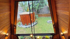 A wooden interior with a view of a garden, a welcome mat, and a hanging light fixture. - Hidden Luxury Cabin in Nature Jacuzzi, Fire Pit & Private Escape (Gobierno Regional de Lima)