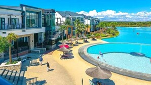 A resort with a large pool, modern buildings, and a clear blue sky. - Luxury 1BR at Blyde Lagoon, Wifi and Security (Pretoria)
