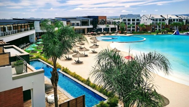 A resort with a large swimming pool, sun loungers, and a view of the surrounding buildings. - Luxury 1BR at Blyde Lagoon, Wifi and Security (Pretoria)