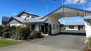 Un motel con entrada cubierta, un cartel y una bandera.