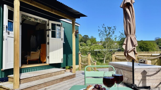 A wooden deck with a table set for two, a chair, and a dining table.