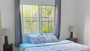 Una camera da letto con un letto, tende, una finestra, un comodino e una lampada.