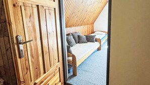 A wooden door leading to a room with a sloped ceiling and a bed with pillows. - Chalet Helena by Interhome (Nové Hamry)