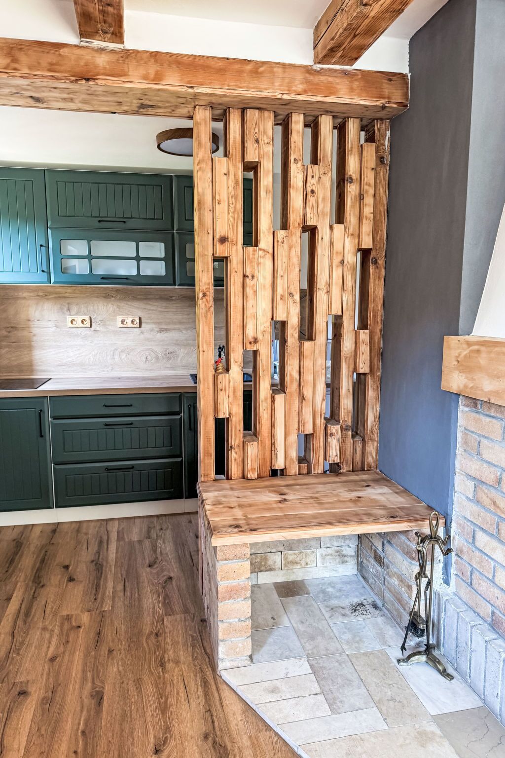 Una cucina con travi in legno, mobili verdi e un camino in pietra.
