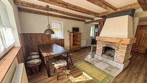 A rustic interior with a wooden dining table, chairs, a fireplace, and a large window. - Chalet Helena by Interhome (Nové Hamry)