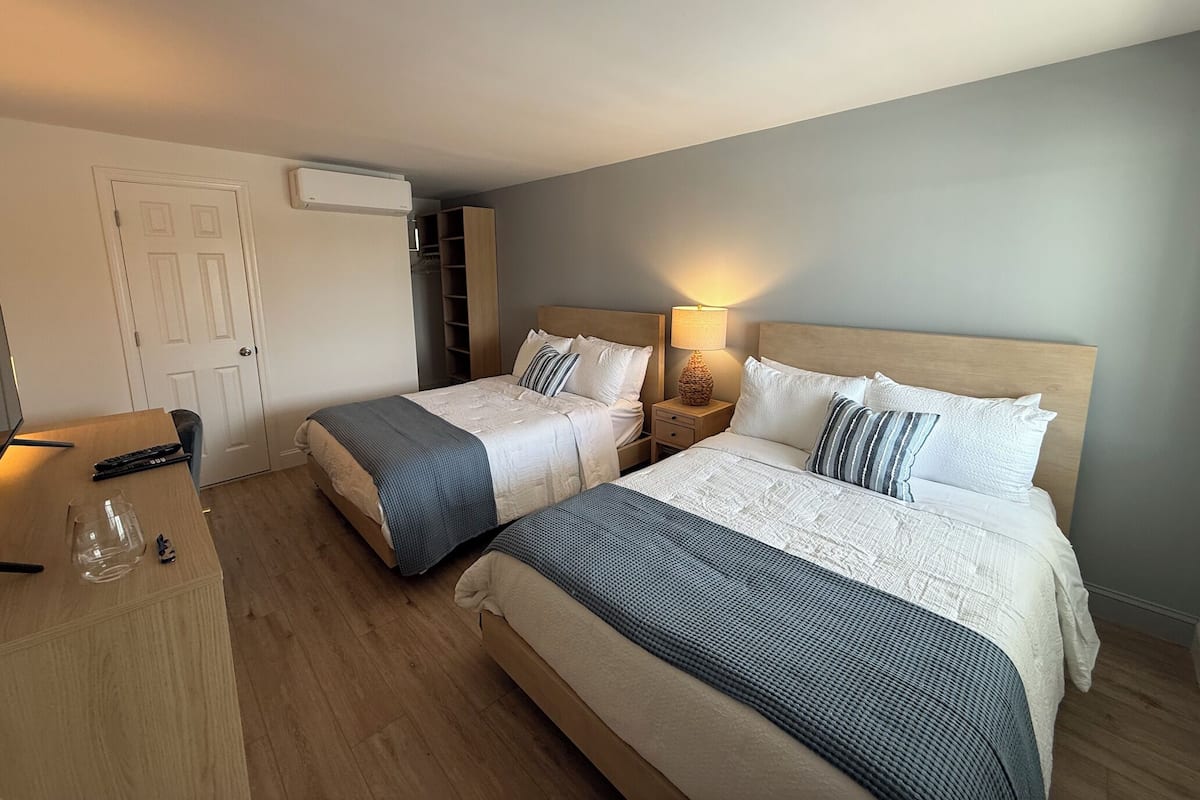 Una habitación de hotel con dos camas, un escritorio, una lámpara y un armario.