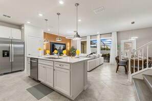 A modern kitchen with a central island, stainless steel appliances, and pendant lighting. - Brand New | 5BR Pool Home w Safari Loft 16200 (Clermont)