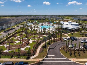 A residential area with a swimming pool, palm trees, and a parking lot. - Brand New | 5BR Pool Home w Safari Loft 16200 (Clermont)