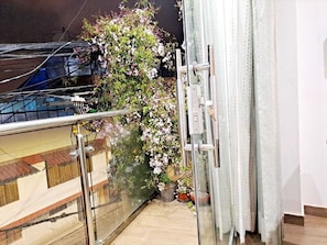 A balcony with a glass railing, a potted plant, and a sliding door. - RESIDENCIAL CRISTINA  (Cusco)