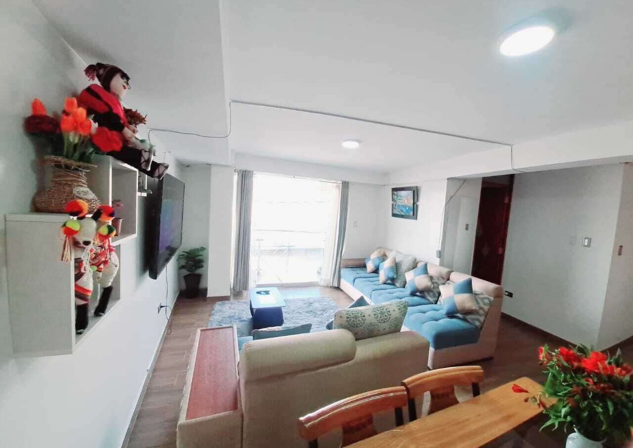 Un salon moderne comprenant un ensemble de canapés, une table basse, un téléviseur et un coin repas avec des chaises et une table.