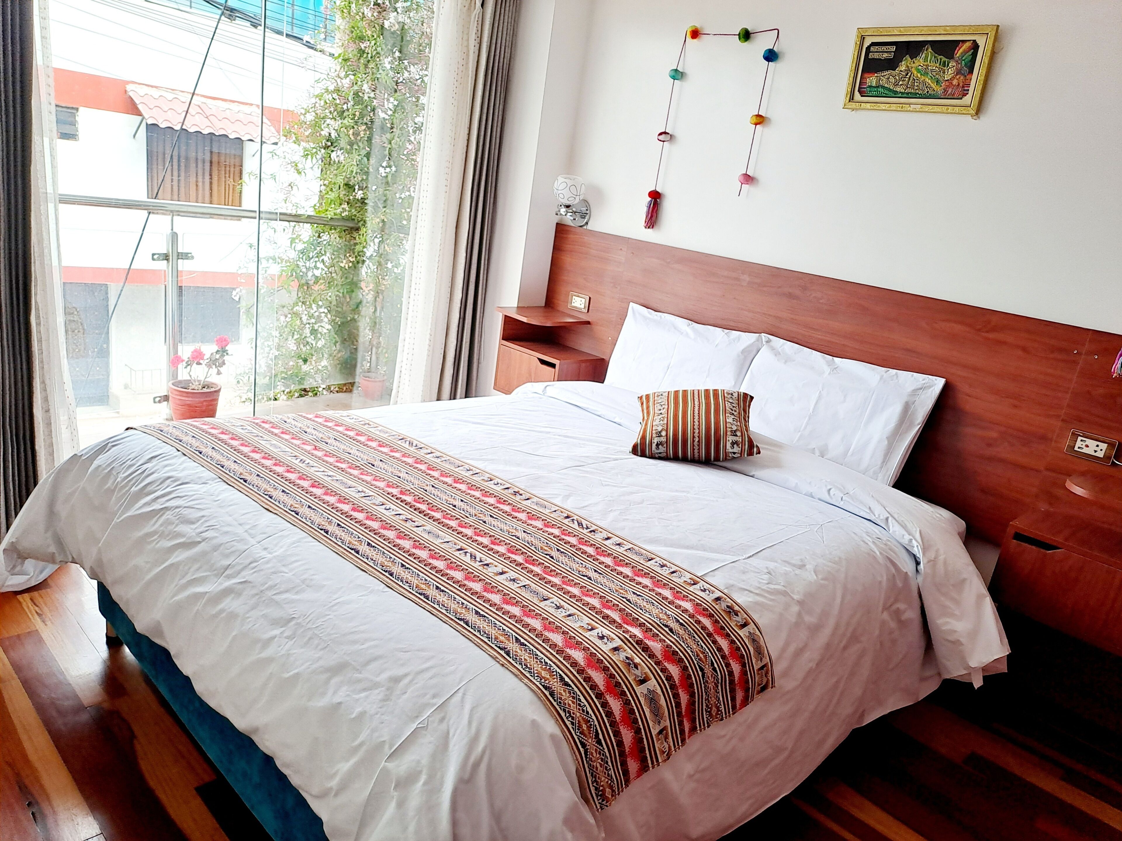 Una cama bien tendida con una colcha estampada, un cabecero de madera y una mesita de noche con una lámpara.