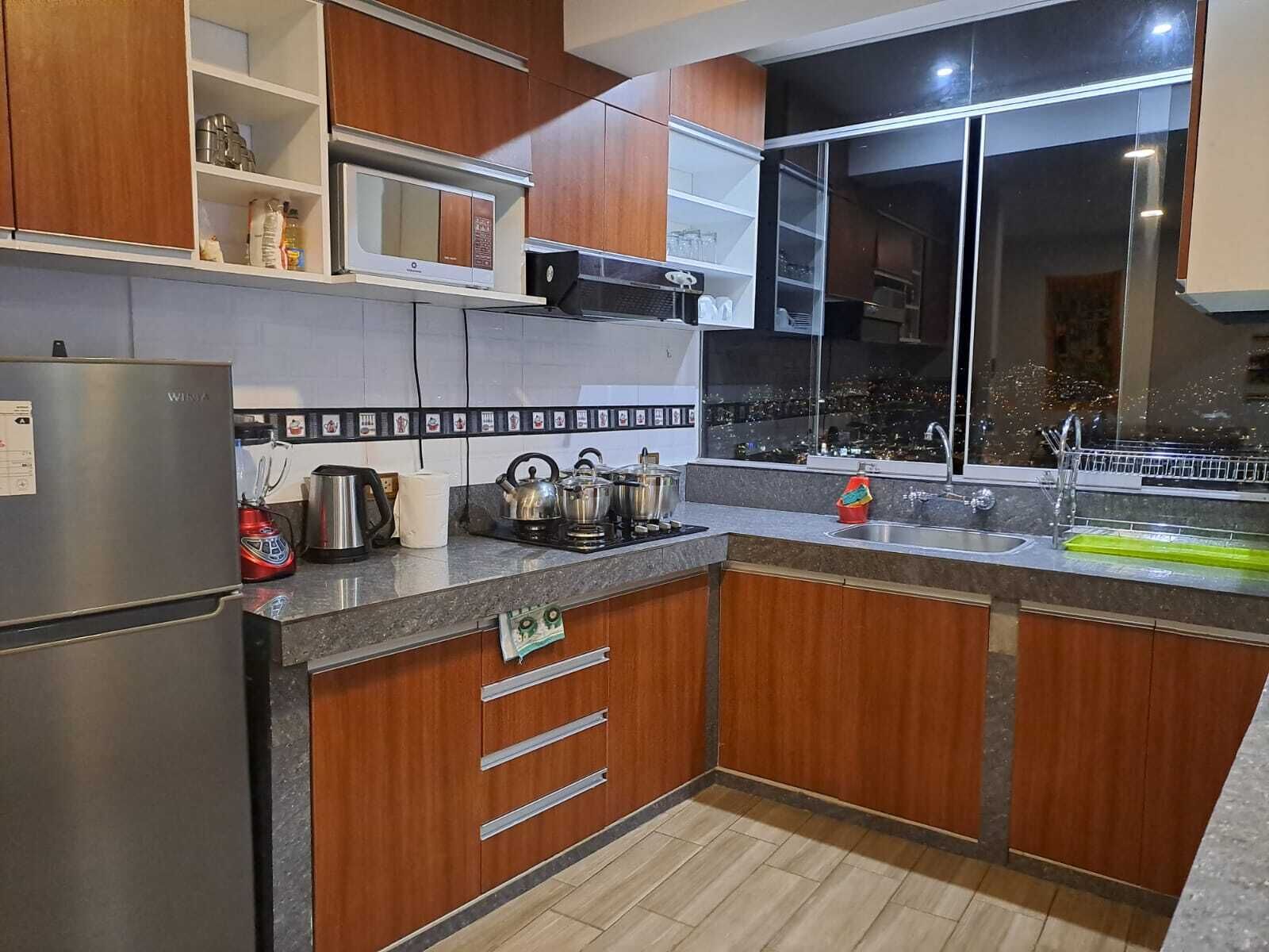 A modern kitchen with wooden cabinets, a stainless steel refrigerator, a microwave, and a gas stove.
