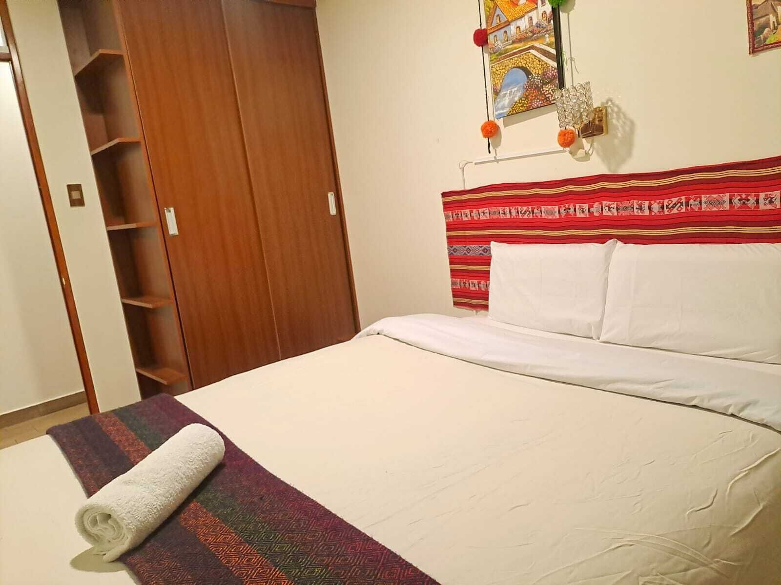 Ein Schlafzimmer mit einem Bett, einem Holzschrank und einem an der Wand hängenden Bild.