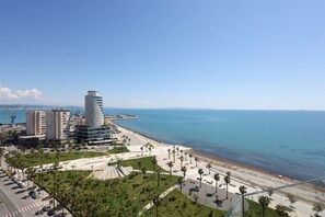 Eine Küstenstadt mit modernen Gebäuden, einer Strandpromenade und blauem, wolkenlosem Himmel.
