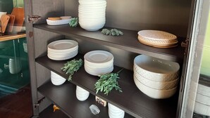 Una cocina con estantes de madera oscura que sostienen platos, cuencos y una copa de vino.