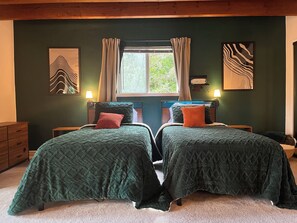 Ein Doppelbett mit grüner Bettwäsche, ein Fenster mit Vorhängen und zwei Wandleuchten.