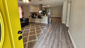 A modern kitchen with a central island, bar stools, and a ceiling fan. - Adorable 3-bedroom 2 bath house with AC calm in wooded area near the Woodlands (Conroe)