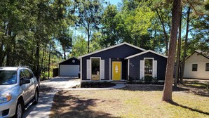 A single-story house with a garage, a driveway, and a well-maintained lawn. - Adorable 3-bedroom 2 bath house with AC calm in wooded area near the Woodlands (Conroe)