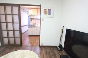 A room with a sliding door leading to a kitchen, a television, and a white fluffy rug. - Right near Ikebukuro! 1-minute walk from Nakamurabashi Station / 8 guests (練馬区中村北3丁目)