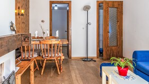 Een eetgedeelte met een houten tafel en stoelen, een vloerlamp en een blauwe bank.
